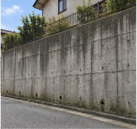 コンクリート擁壁の例。水抜き穴のあるコンクリート壁の上に住宅が建っている